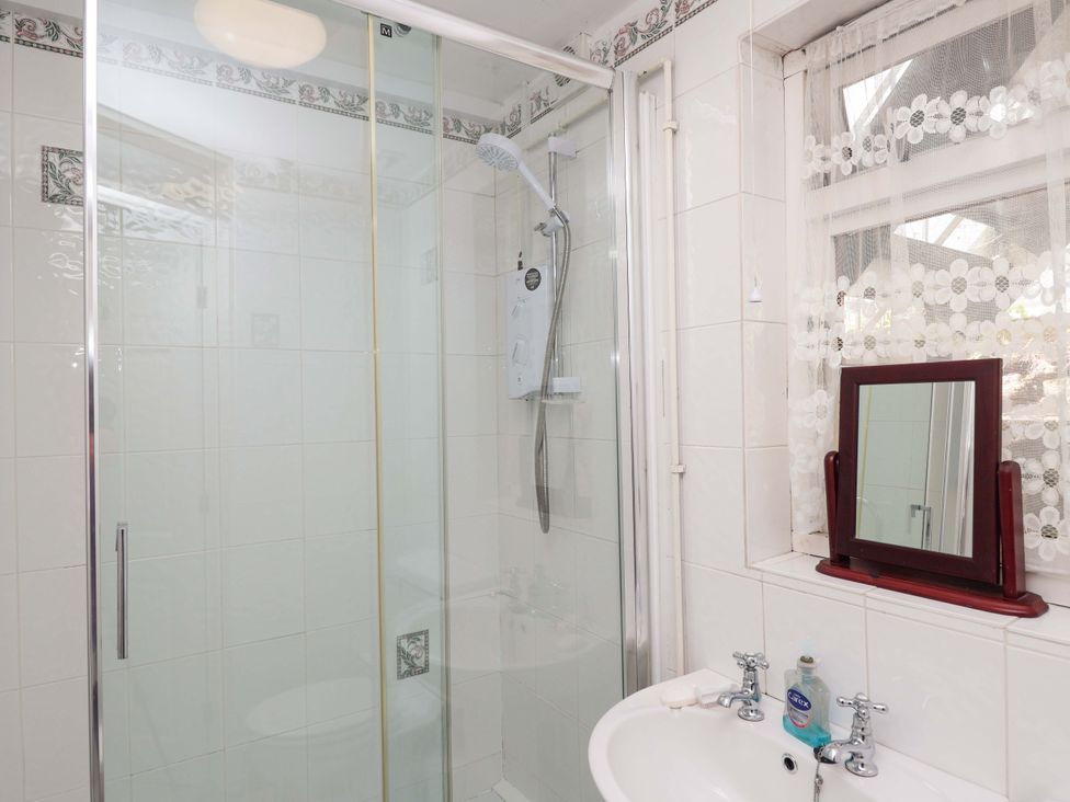 A bathroom with a shower, sink and mirror at Agar Cottage, Trelights, near Port Isaac