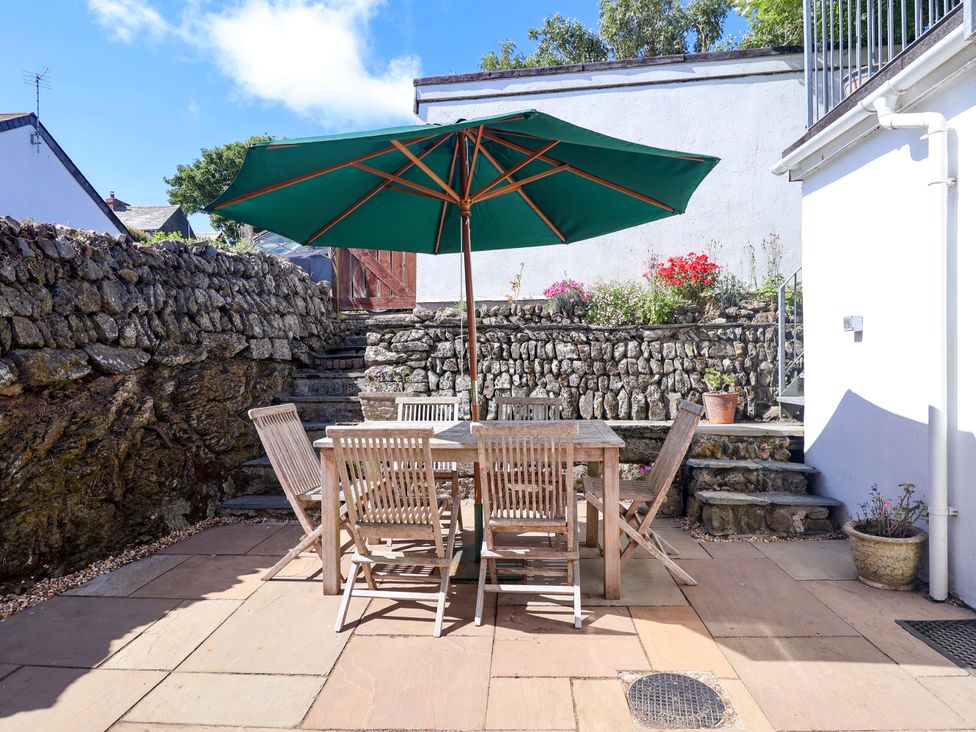 A garden with a table and chairs under an umbrella at Agar Cottage, Trelights, near Port Isaac