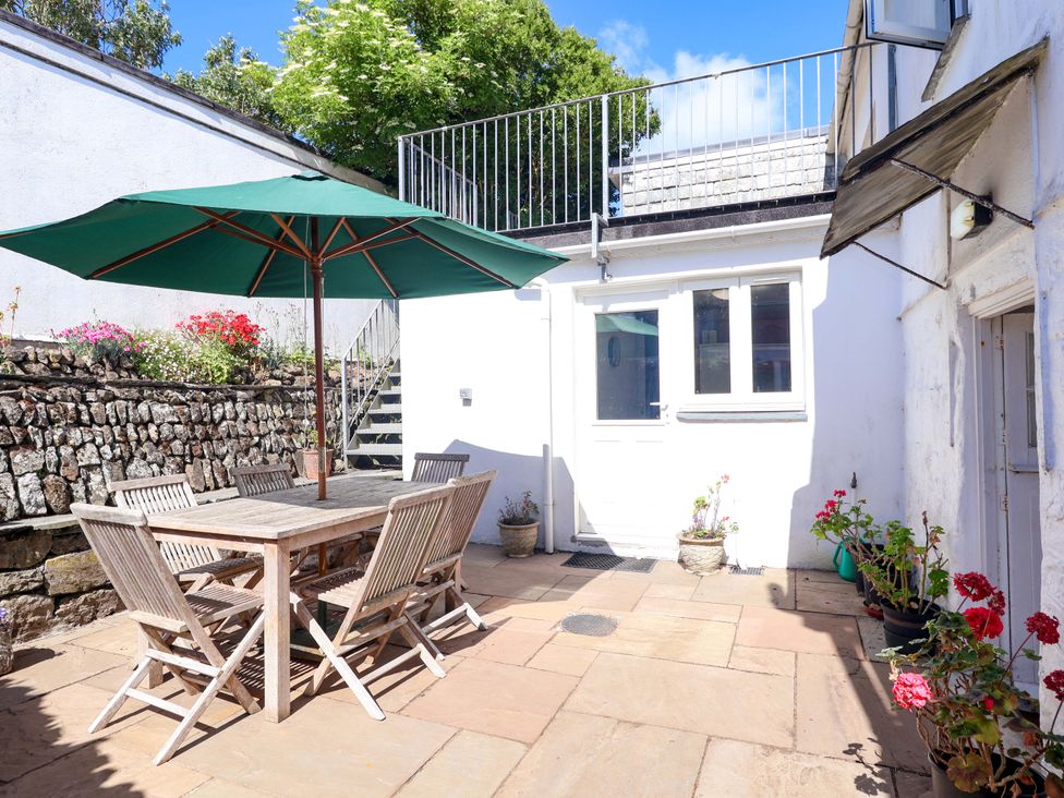 An outdoor patio with a table and chairs under an umbrella at Agar Cottage, Trelights, near Port Isaac