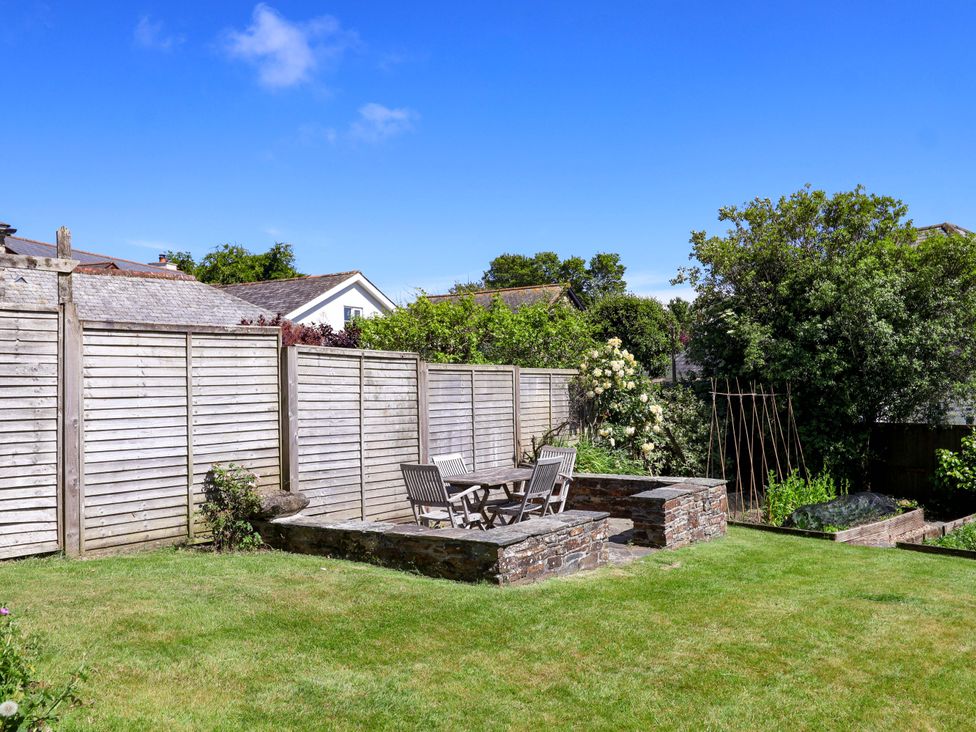 A garden with a table and chairs with a fence at Agar Cottage in Trelights, near Port Isaac