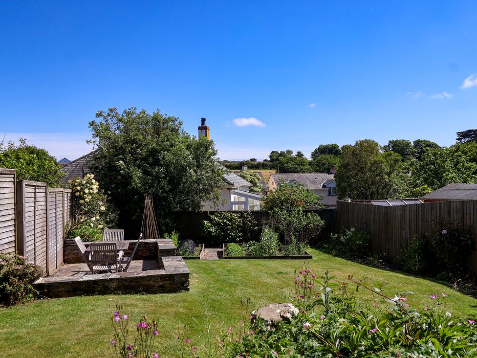 A garden with a patio and flower beds at Agar Cottage, Trelights, near Port Isaac