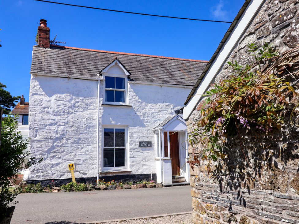 A cottage with a sign and a stone wall at Agar Cottage Trelights near Port Isaac