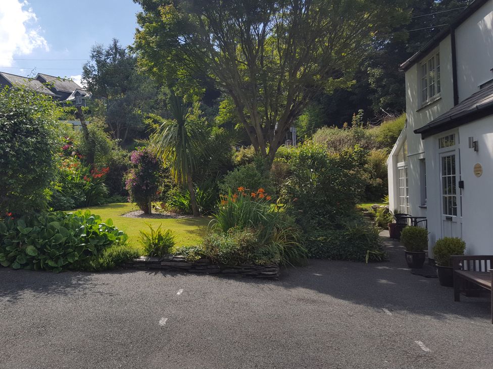 A garden with various plants and a house at Orchard Lodge in Boscastle