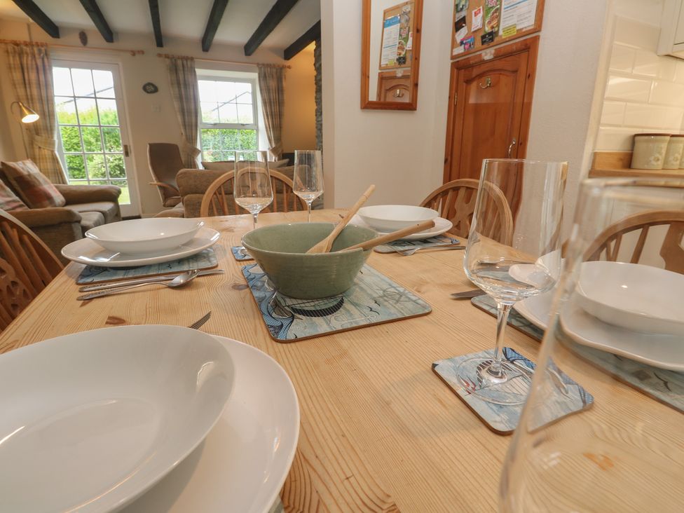 A dining table set with plates and glasses at Primrose Cottage, Edmonton, near Wadebridge
