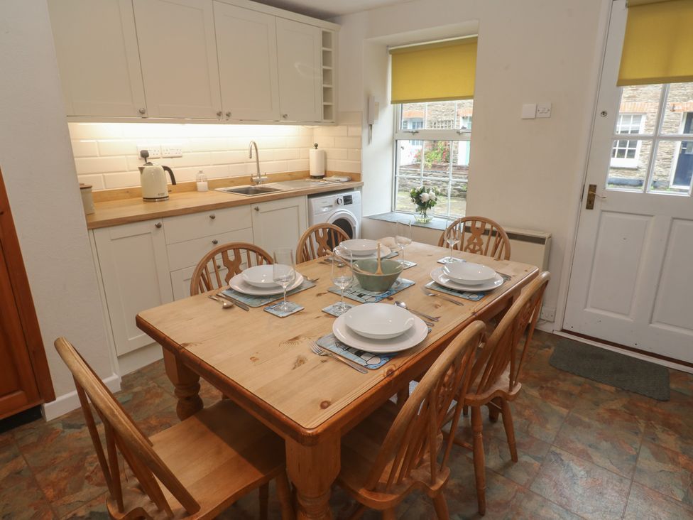 A kitchen with dining table and chairs at Primrose Cottage in Edmonton, near Wadebridge