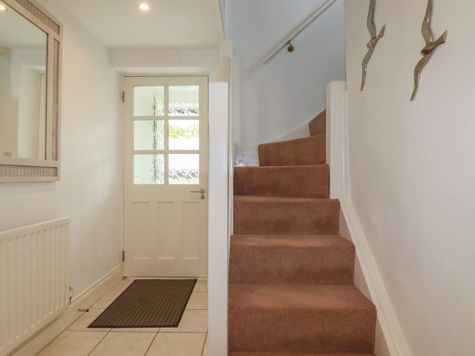 A hallway with a staircase and a door at Atlantic View in Tintagel