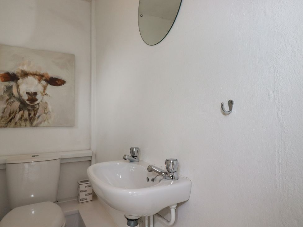 A bathroom with a toilet, sink, and painting at Atlantic View in Tintagel