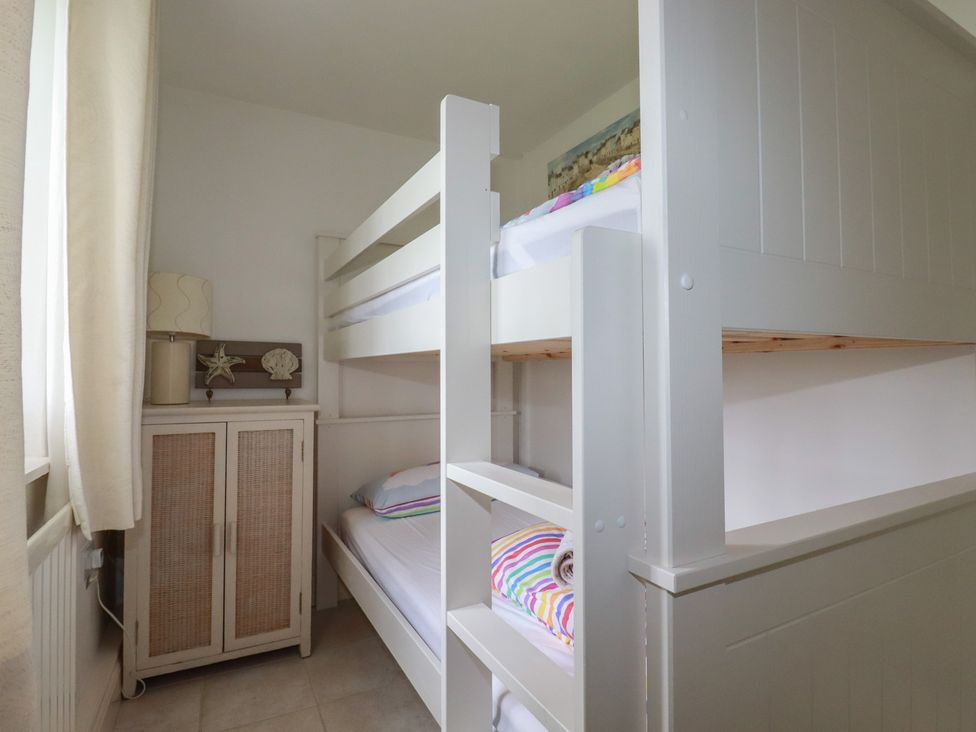 A bedroom with a bunk bed and storage cabinet at Atlantic View in Tintagel