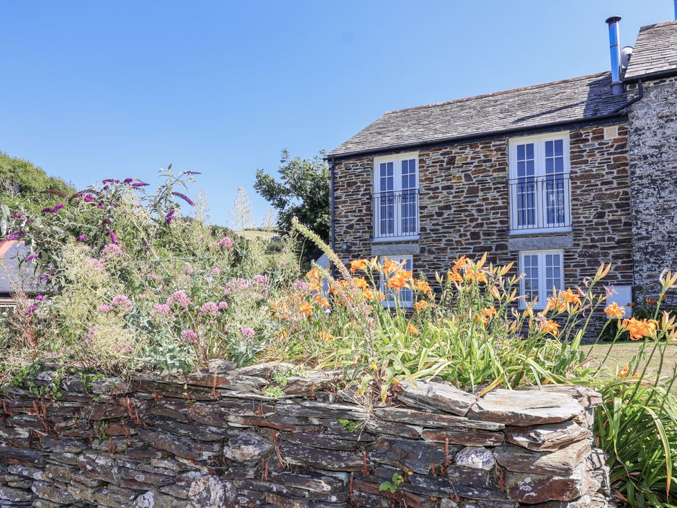 A garden with flowers and a stone wall at Atlantic View in Tintagel