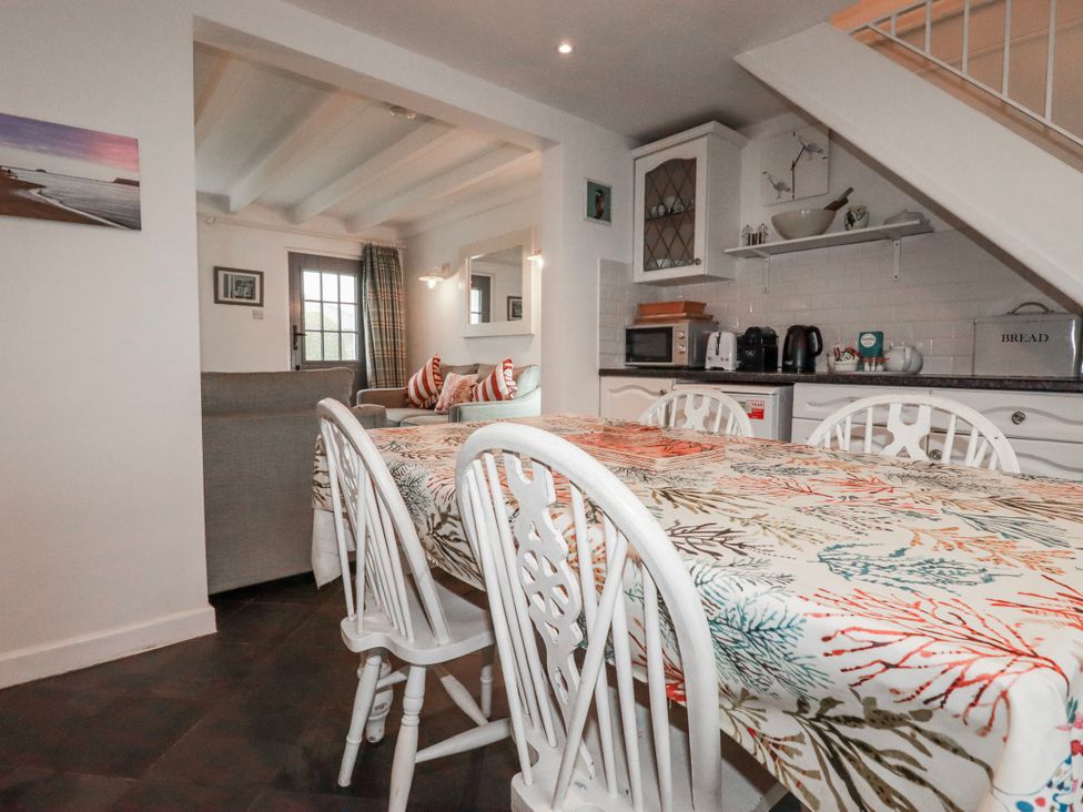 A kitchen with a dining table and chairs at Kingfisher Cottage in Edmonton, near Wadebridge