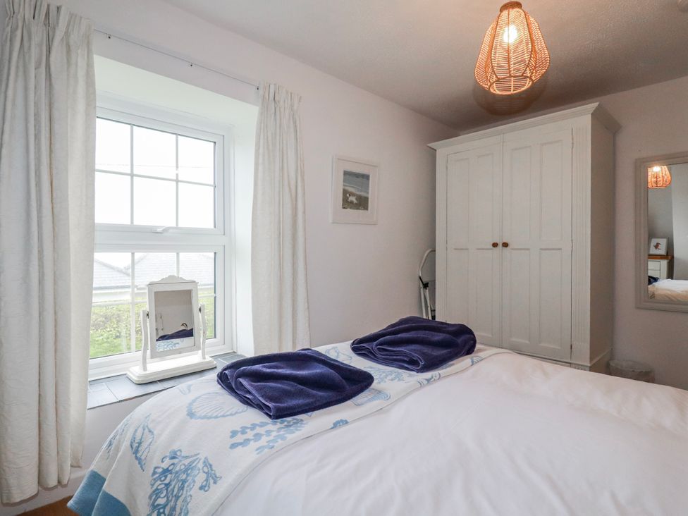 A bedroom with a bed and window at Kingfisher Cottage in Edmonton, near Wadebridge