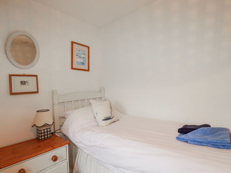 A bedroom with a bed and decorative items at Kingfisher Cottage in Edmonton, near Wadebridge