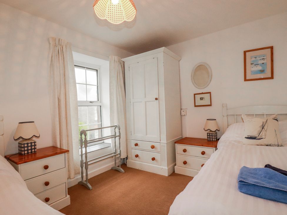 A bedroom with two beds and a wardrobe at Kingfisher Cottage in Edmonton, near Wadebridge