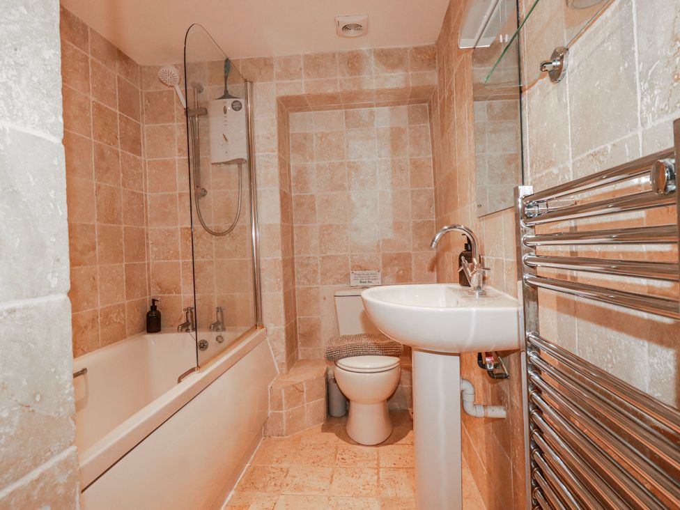 A bathroom with a bathtub, shower, toilet, and sink at Kingfisher Cottage, Edmonton, near Wadebridge