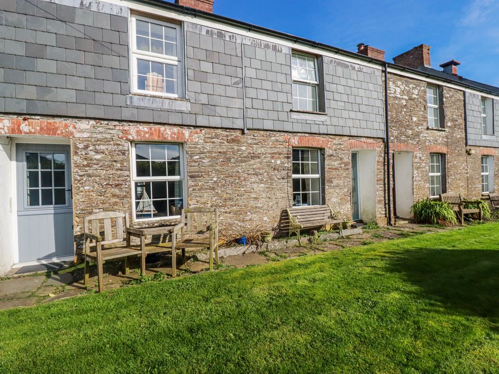 An exterior view of a building with benches and a table at Kingfisher Cottage, Edmonton, near Wadebridge