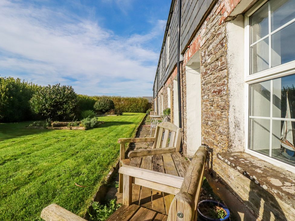 A garden with a wooden bench and grass at Kingfisher Cottage in Edmonton, near Wadebridge