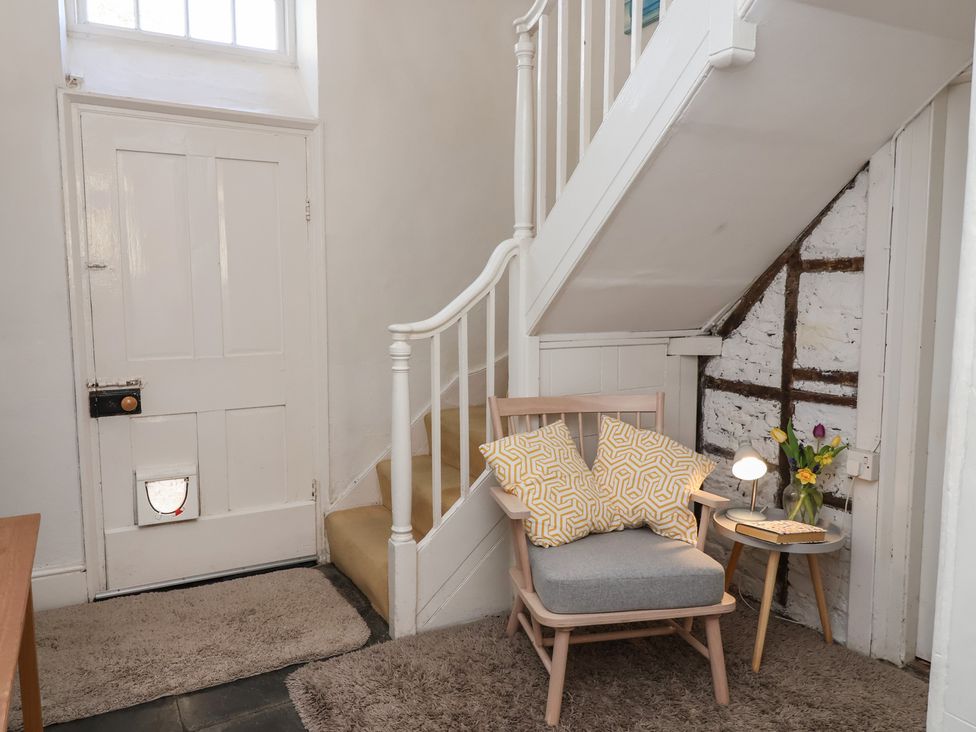 A hallway with a staircase and a chair at Tregonhawke Farmhouse in Millbrook