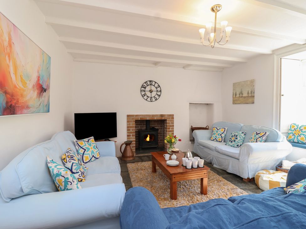A living room with a sofa, table, and fireplace at Tregonhawke Farmhouse in Millbrook