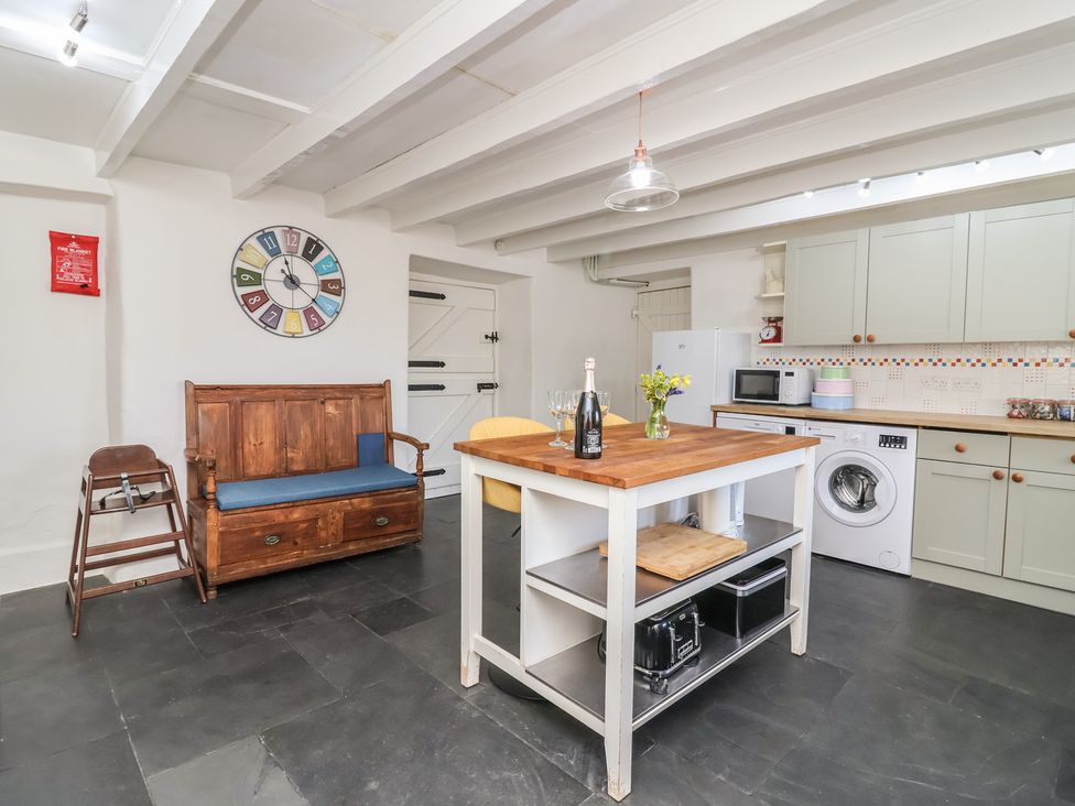 A kitchen with a clock, bench and kitchen island at Tregonhawke Farmhouse in Millbrook