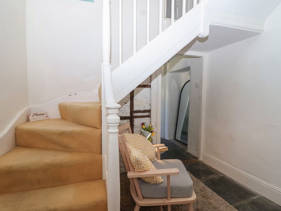 A hallway with staircase and chair at Tregonhawke Farmhouse in Millbrook