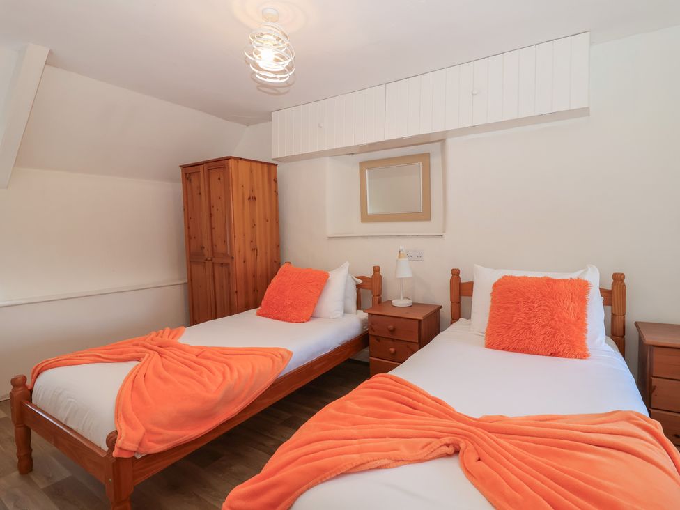 A bedroom with two single beds and wooden furniture at Tregonhawke Farmhouse in Millbrook