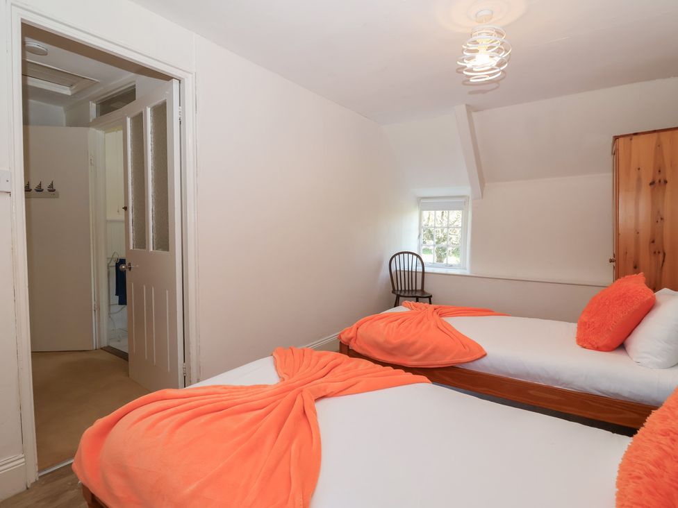 A bedroom with two beds and a chair at Tregonhawke Farmhouse in Millbrook