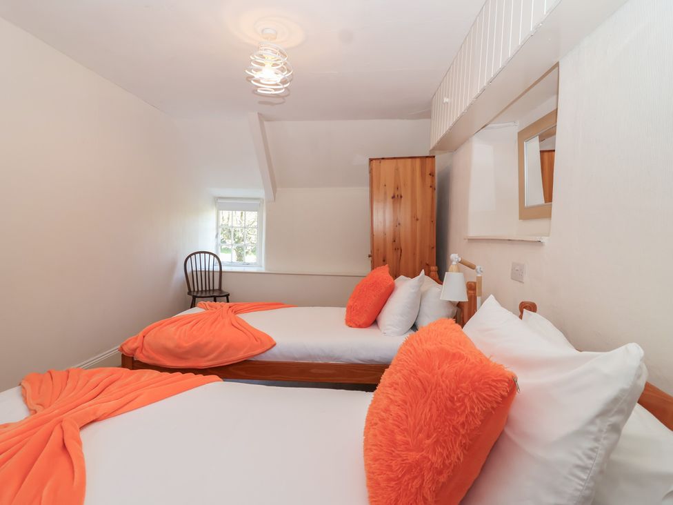 A bedroom with two beds and a wardrobe at Tregonhawke Farmhouse in Millbrook