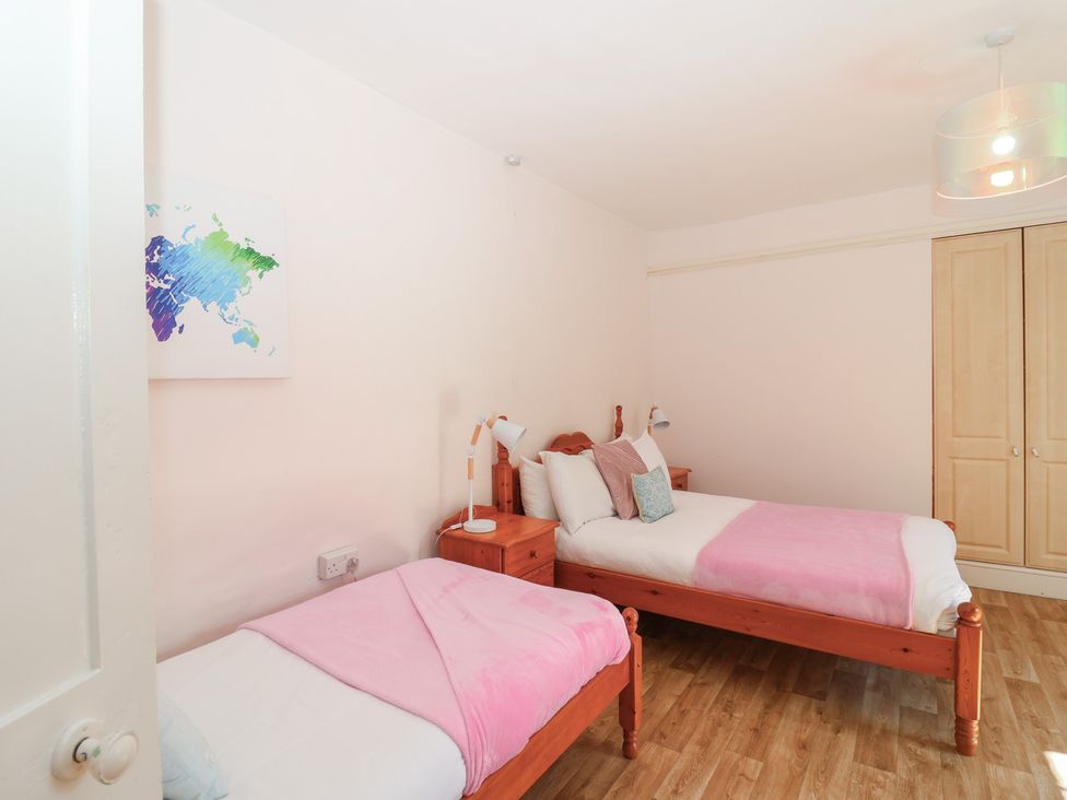 A bedroom with two beds and a wardrobe at Tregonhawke Farmhouse, Millbrook