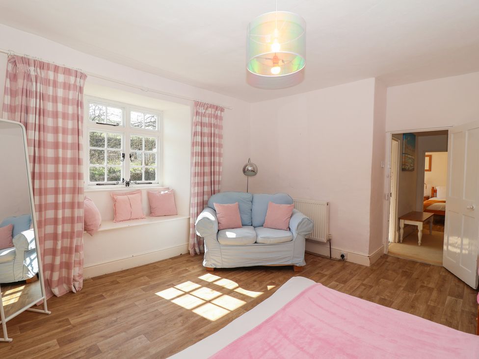 A bedroom with a sofa and mirror at Tregonhawke Farmhouse, Millbrook