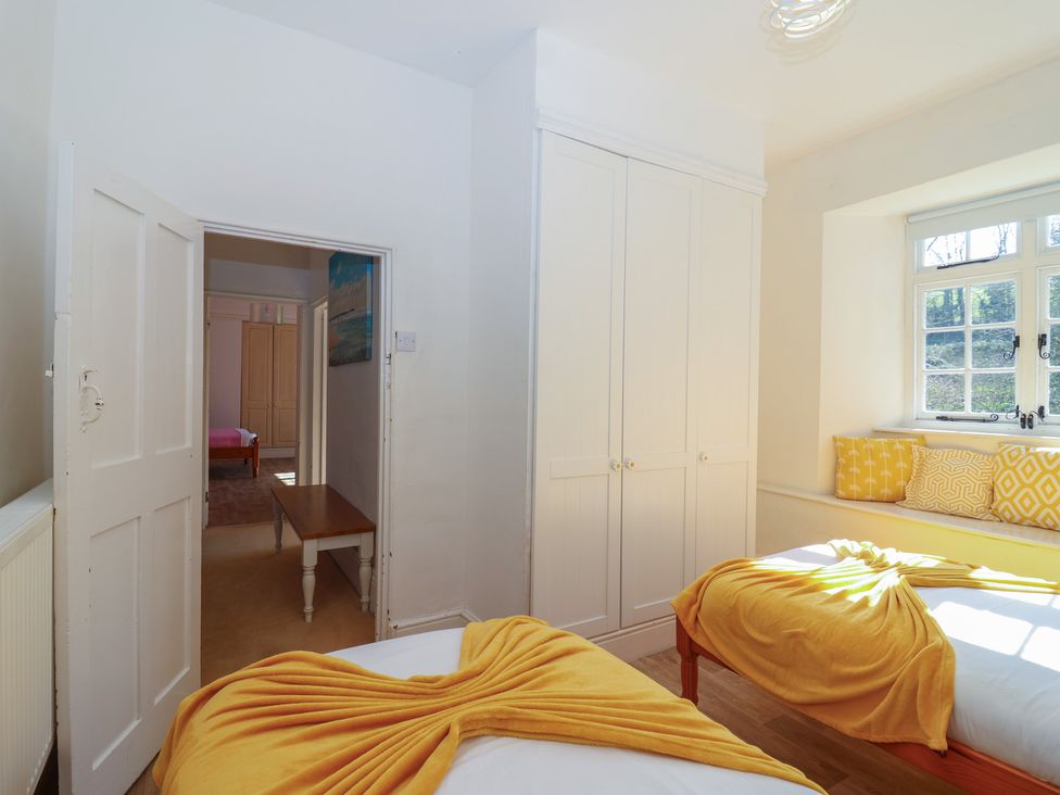 A bedroom with two beds and a wardrobe at Tregonhawke Farmhouse in Millbrook