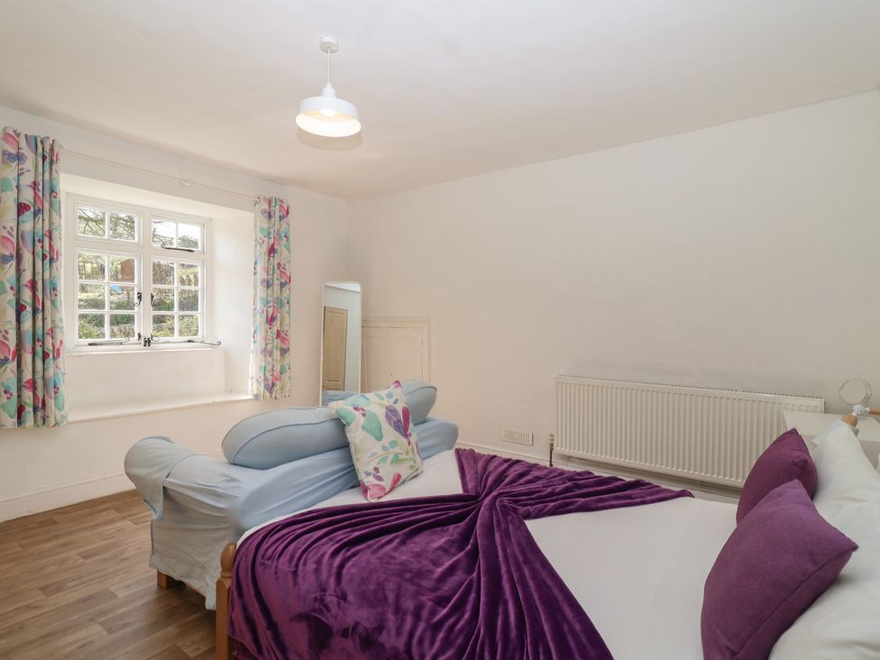 A bedroom with a bed, sofa, curtains and a mirror at Tregonhawke Farmhouse in Millbrook