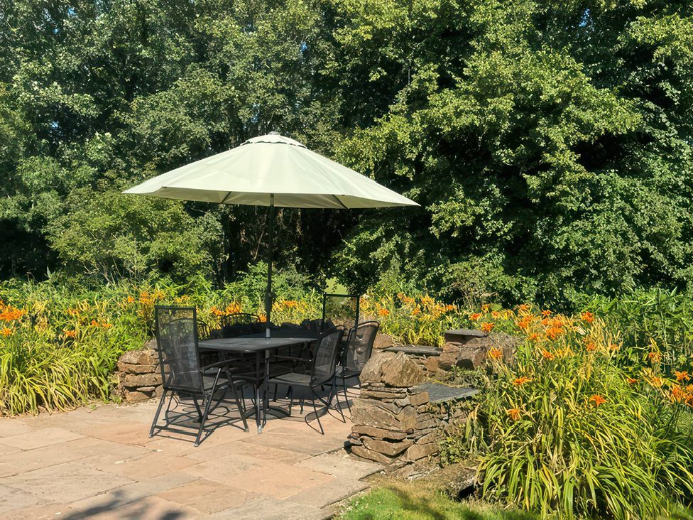 An outdoor seating area with a table and chairs under an umbrella at Kingbarth in Lerryn
