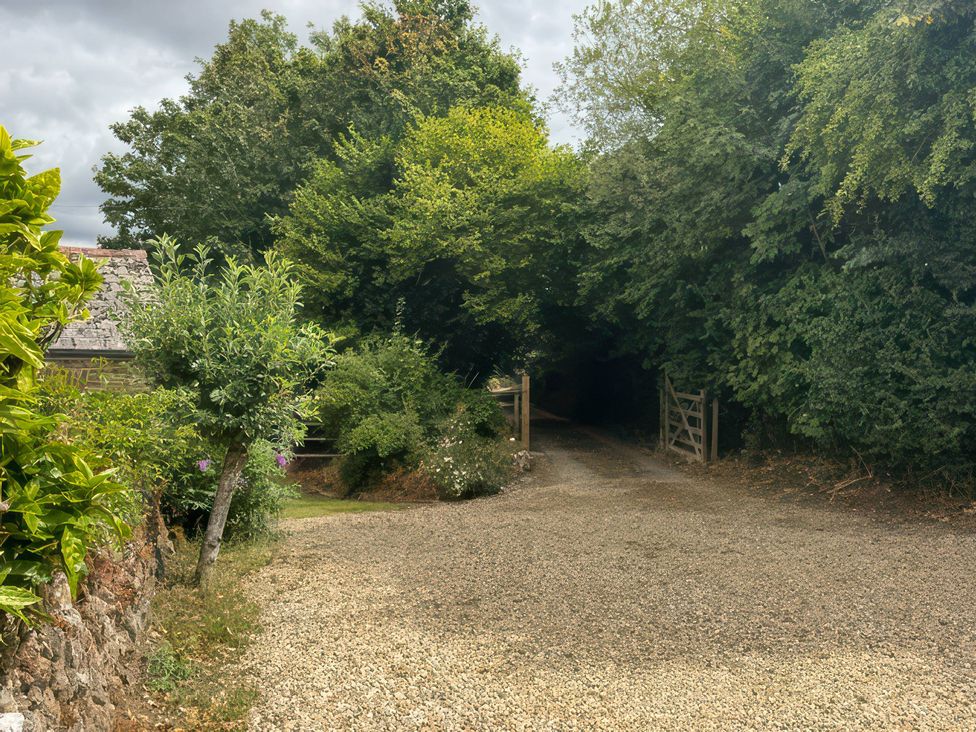 A path leading to a gate surrounded by trees and bushes at Kingbarth in Lerryn