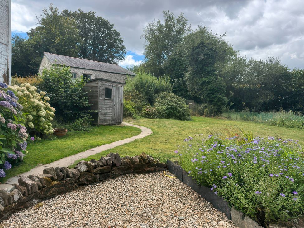 A garden with a shed and flowers at Kingbarth in Lerryn