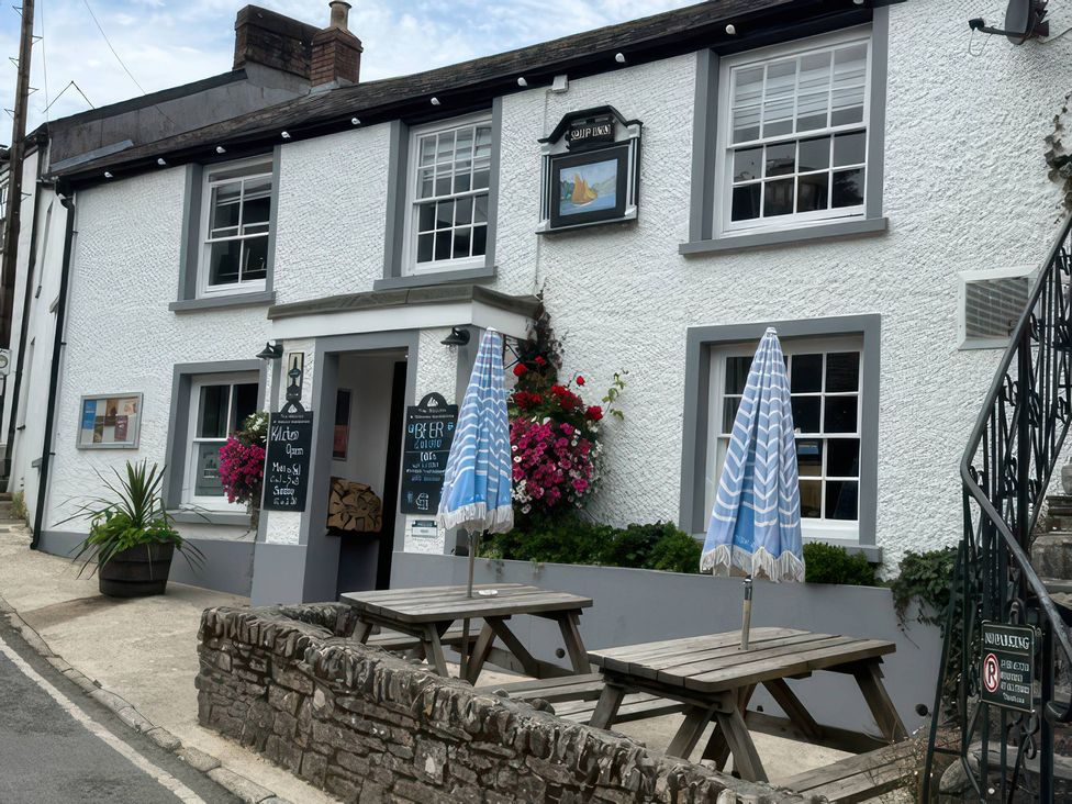 An outdoor seating area of a pub with tables and umbrellas at Kingbarth in Lerryn