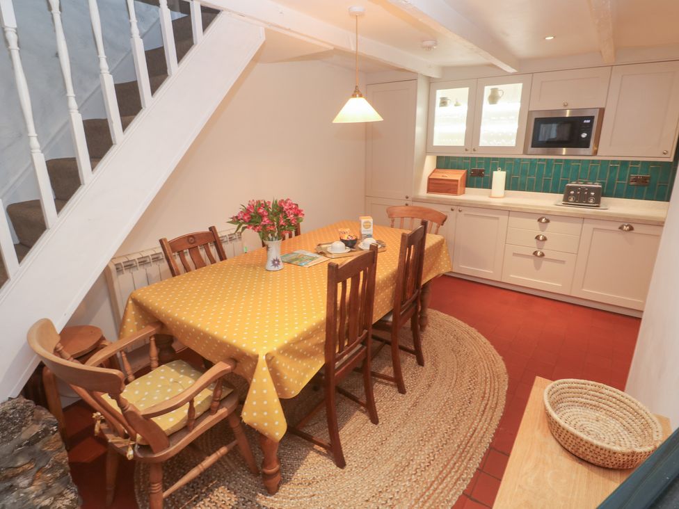 A kitchen with a dining table and chairs at Mural Cottage in Mousehole