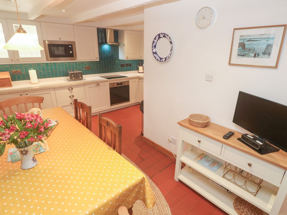 A kitchen with a table and chairs at Mural Cottage in Mousehole