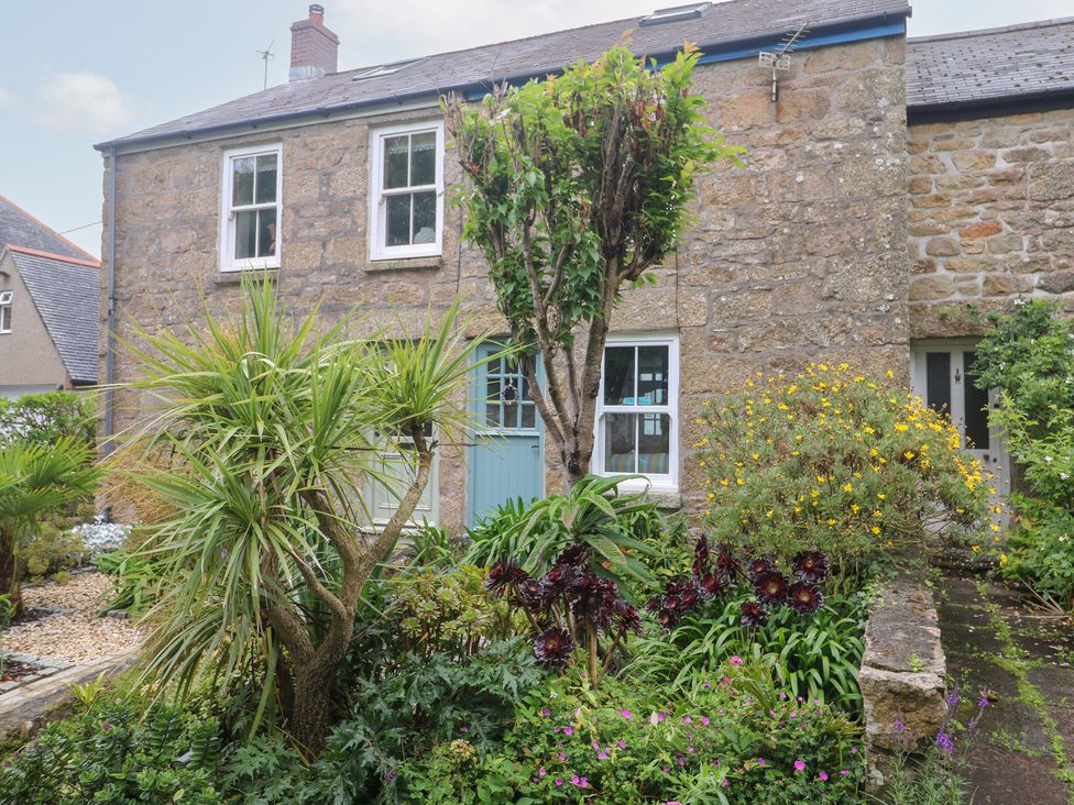 A garden with plants and a stone house at 2 The Cottages Ludgvan
