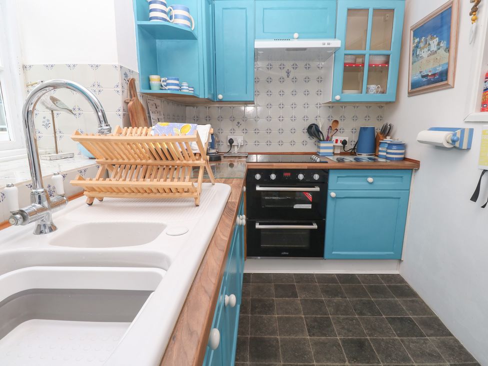 A kitchen with blue cabinetry and appliances at 2 The Cottages Ludgvan