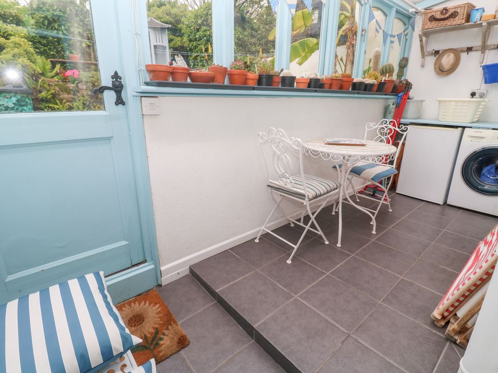 A conservatory with a table and chairs and a washing machine at 2 The Cottages Ludgvan