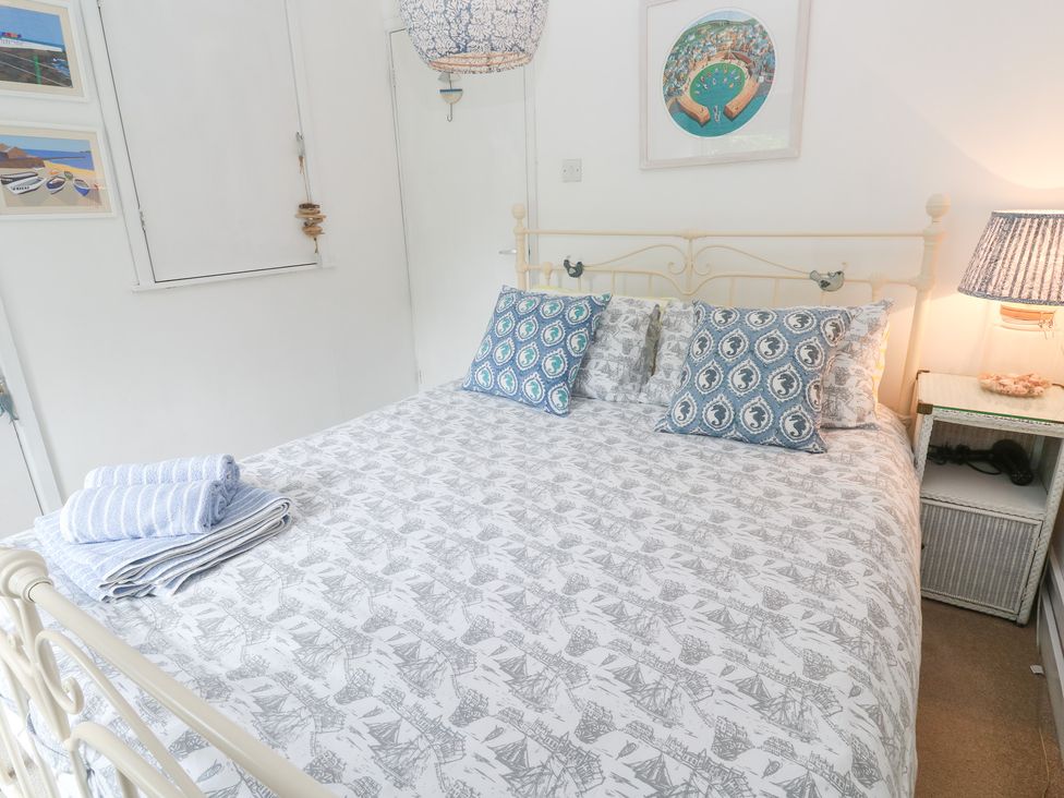 A bedroom with a bed and side table at 2 The Cottages Ludgvan