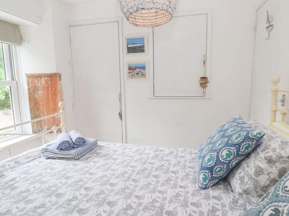 A bedroom with a bed, pillows, and towels at 2 The Cottages Ludgvan