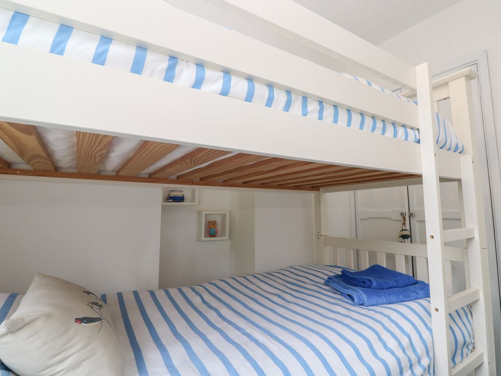 A bunk bed with striped bedding and towels at 2 The Cottages Ludgvan