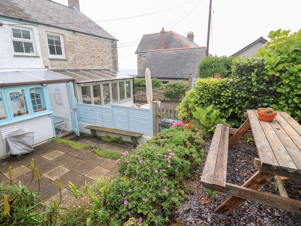 A garden with flowers and a wooden bench at 2 The Cottages Ludgvan