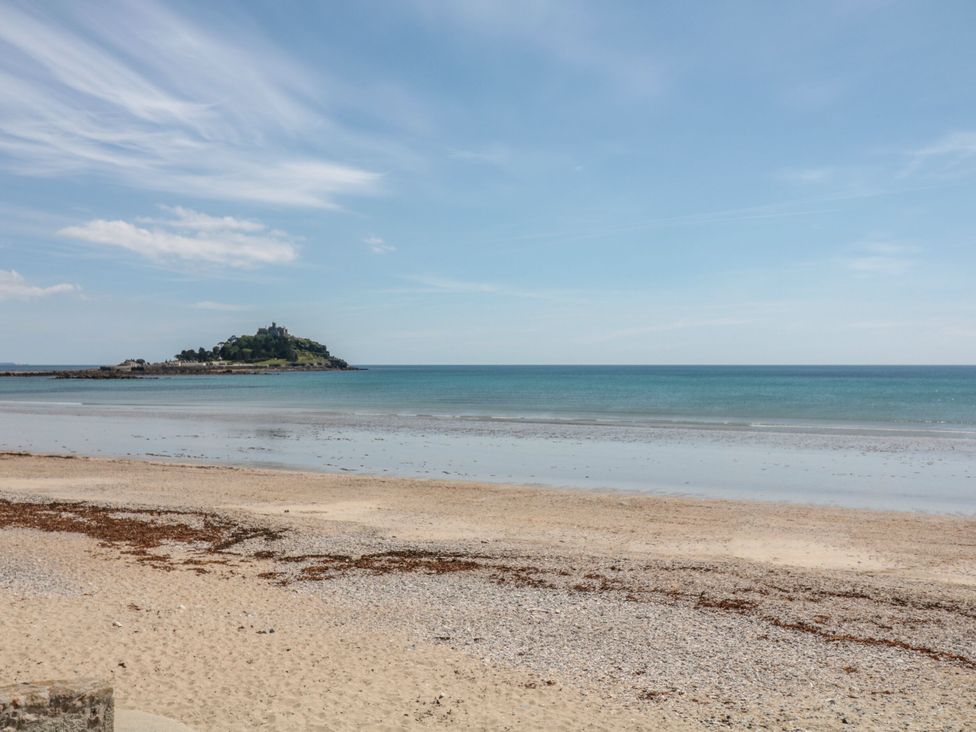 A view of a beach and ocean with an island in the distance at 2 The Cottages Ludgvan