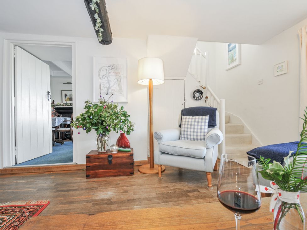 A living room with a chair, lamp, and flower vase at Clamoak Cottage near Bere Alston