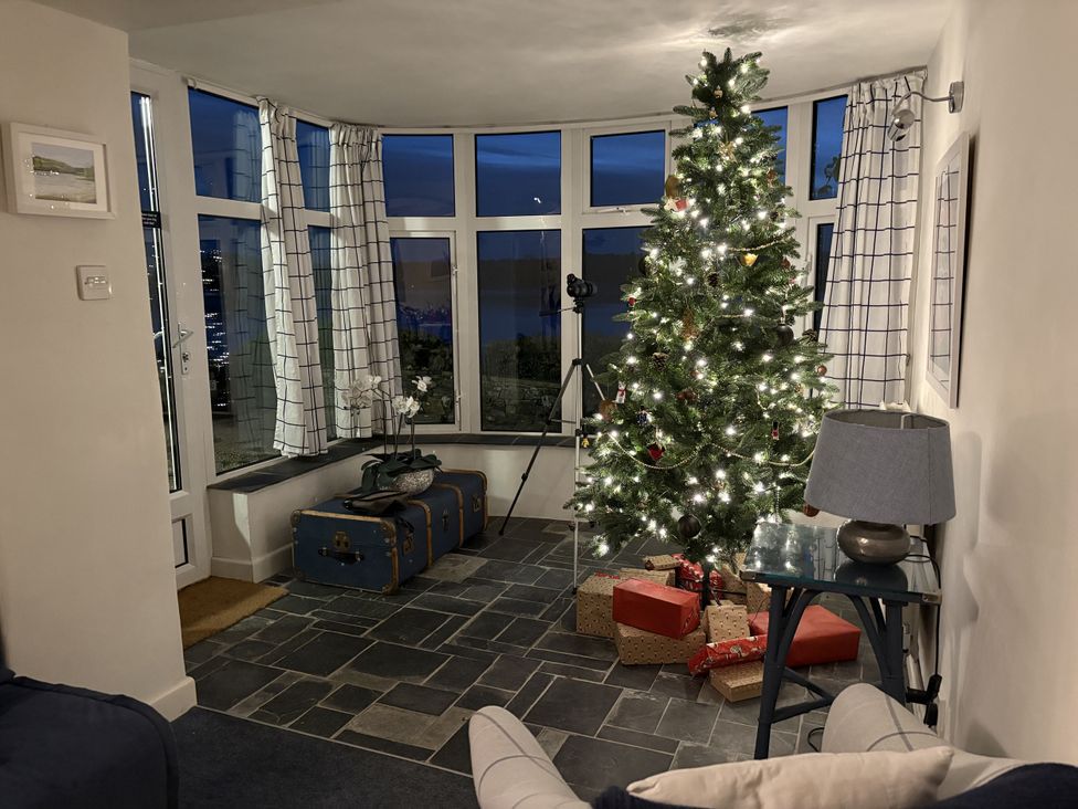 A living room with a Christmas tree and presents at Clamoak Cottage near Bere Alston