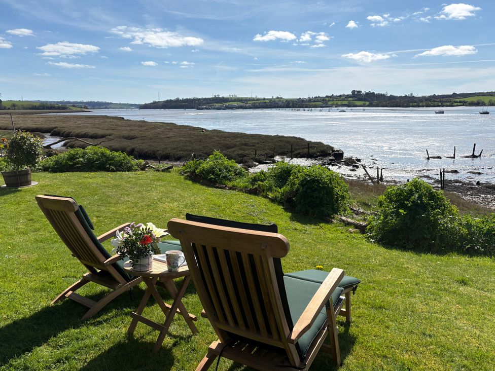 Chairs and a table overlooking a river at Clamoak Cottage near Bere Alston