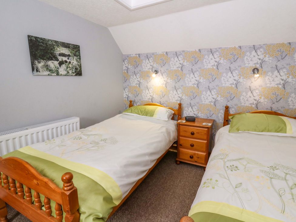 A bedroom with two beds and a nightstand at Old Farmhouse Cottage