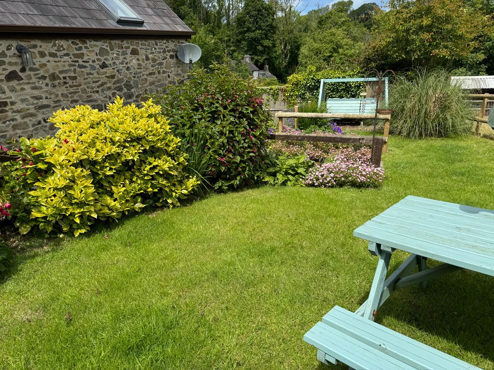 A garden with grass, flowers, bushes, and a picnic table at Old Farmhouse Cottage